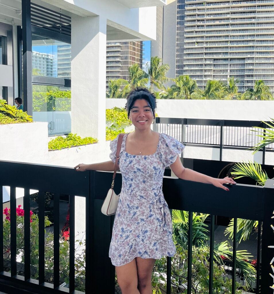Saima poses for a headshot wearing a white dress with flowers.